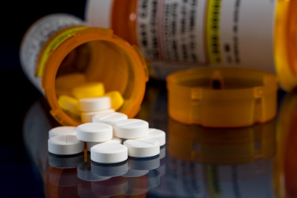 A pill bottle with medication spread out to illustrate prescription drug crimes san diego