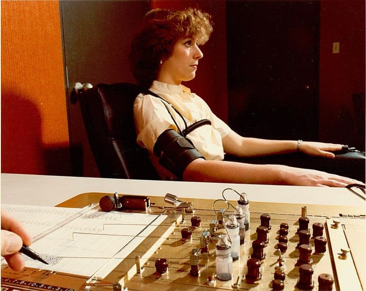 A woman sitting at a polygraph machine.