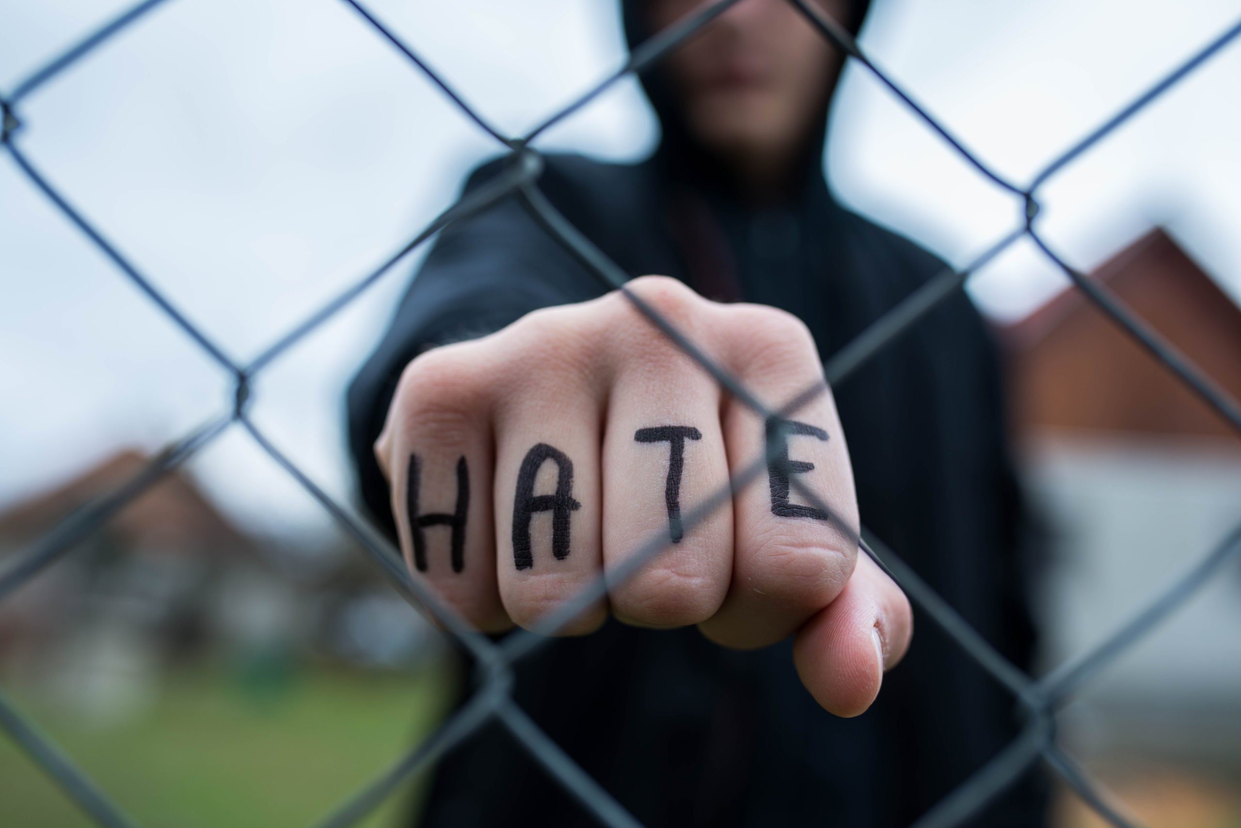 Man with "hate" on knuckles to illustrate San Diego hate crime defense attorney