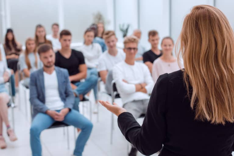 A woman talks in front of a group of seated people