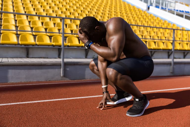 A man crouches in a track and field stadium