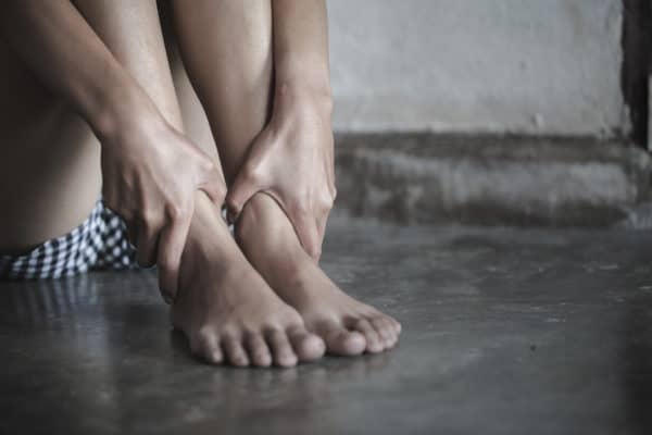 Mujer agachada sujetándose los tobillos
