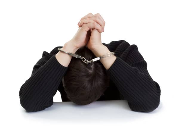 Hombre esposado escondiendo su cabeza
