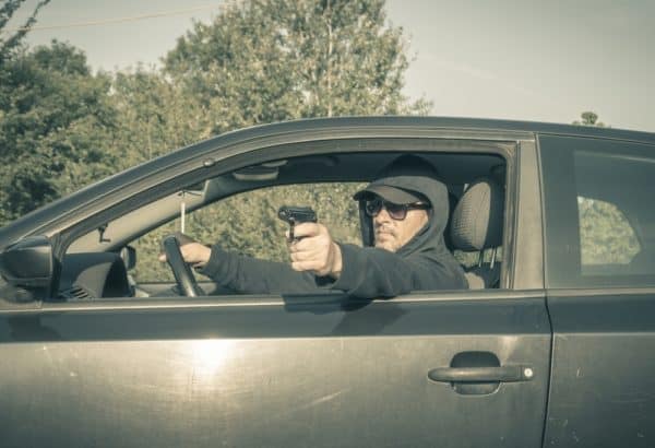Hombre sujetando una pistola por la ventanilla del coche
