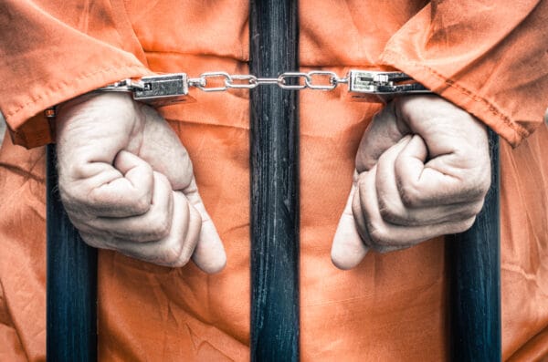 A person in a jumpsuit with handcuffs who could be being charged with resisting an arresting officer